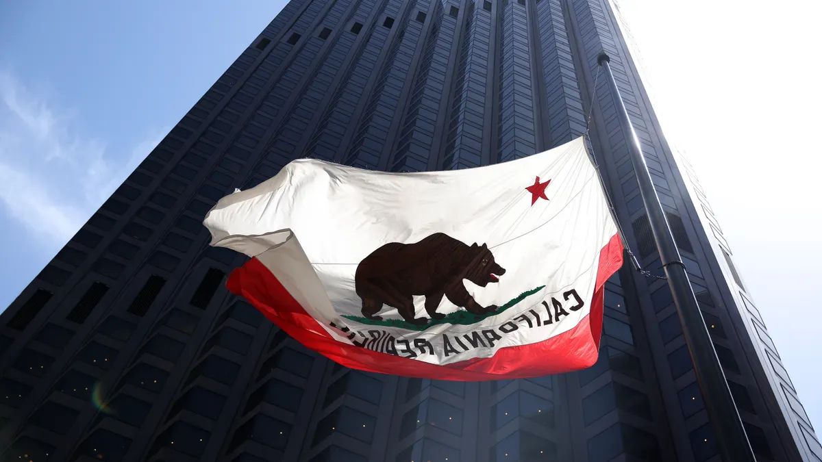 California's flag flies in front of a large commercial building
