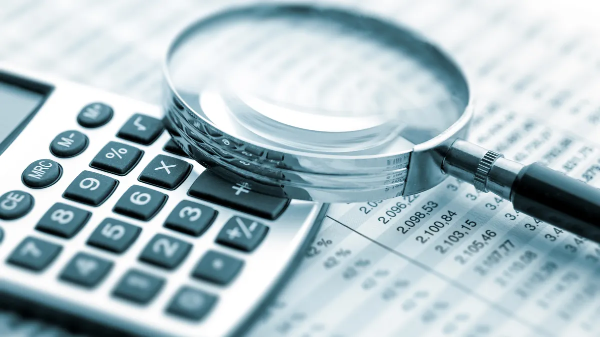A magnifying glass rests on a calculator atop a paper chart.