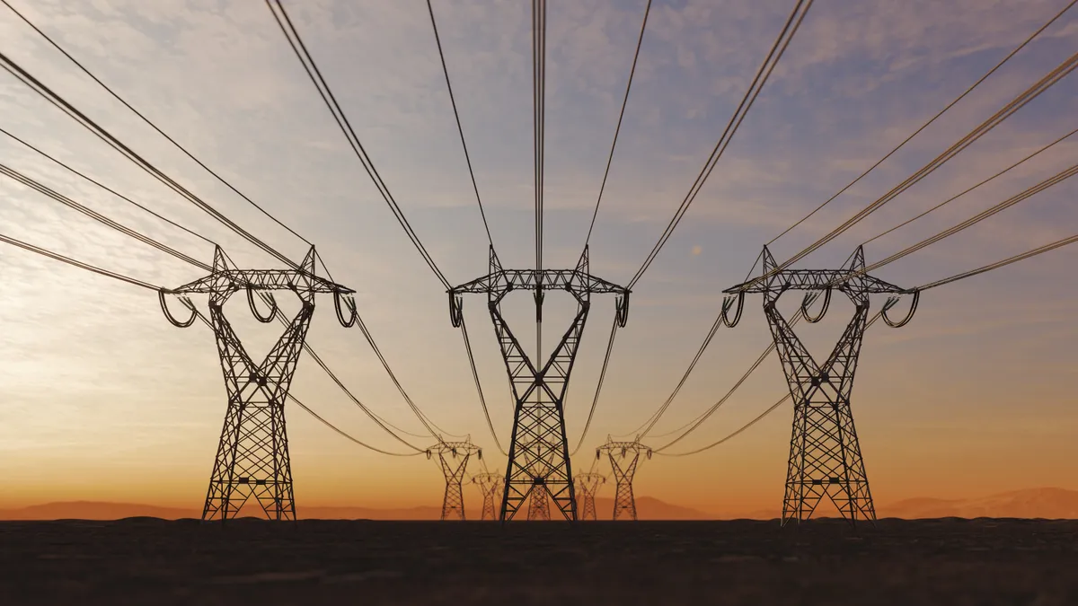 The silhouette of a high voltage power line line towers during sunset.