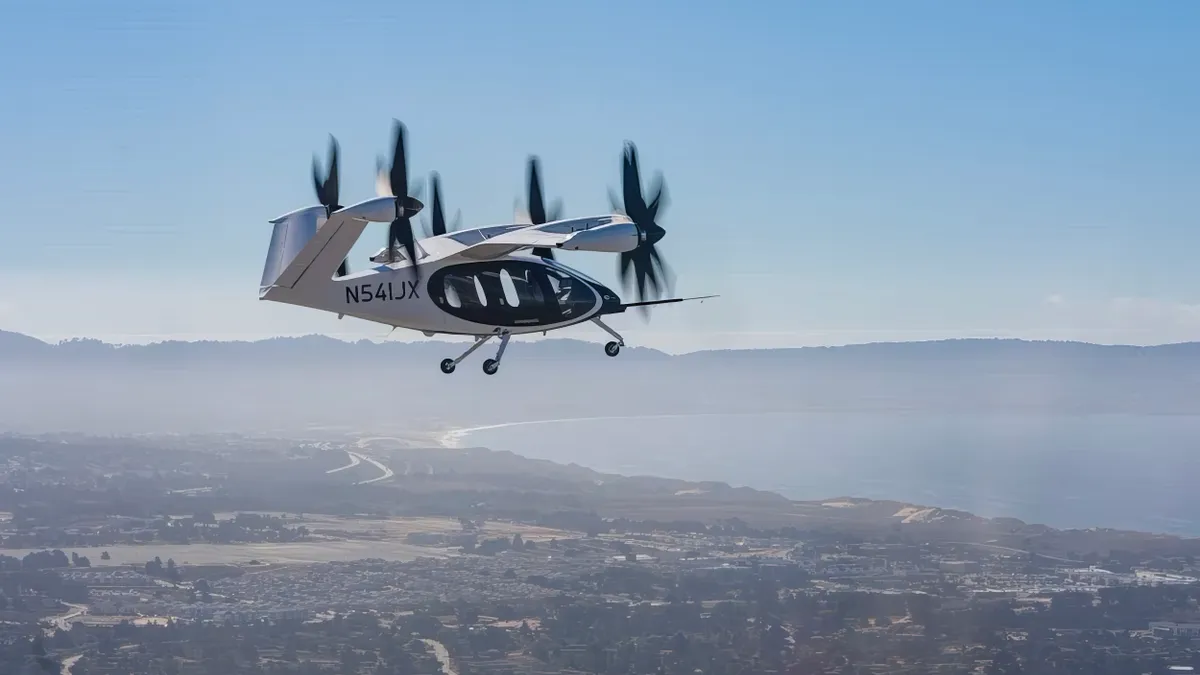 An air taxi flies over suburban homes near the Pacific coast.