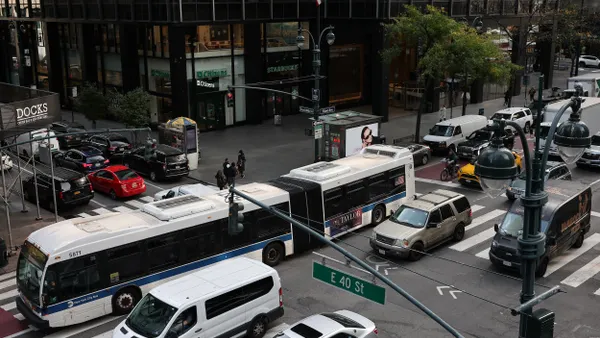 Overhead view of a busy city intersection with an articulated bus and many cars.