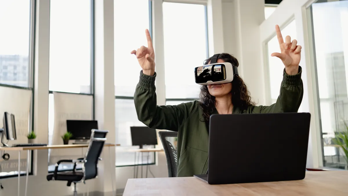 A woman wears VR goggles, her arms are outstretched