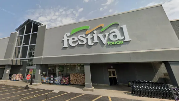 An exterior view of a supermarket with a sign that reads "Festival Foods" on a gray background.