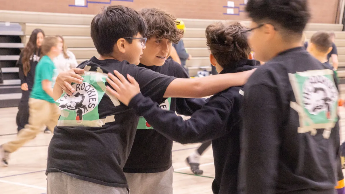 Four students huddle together outside a school building.