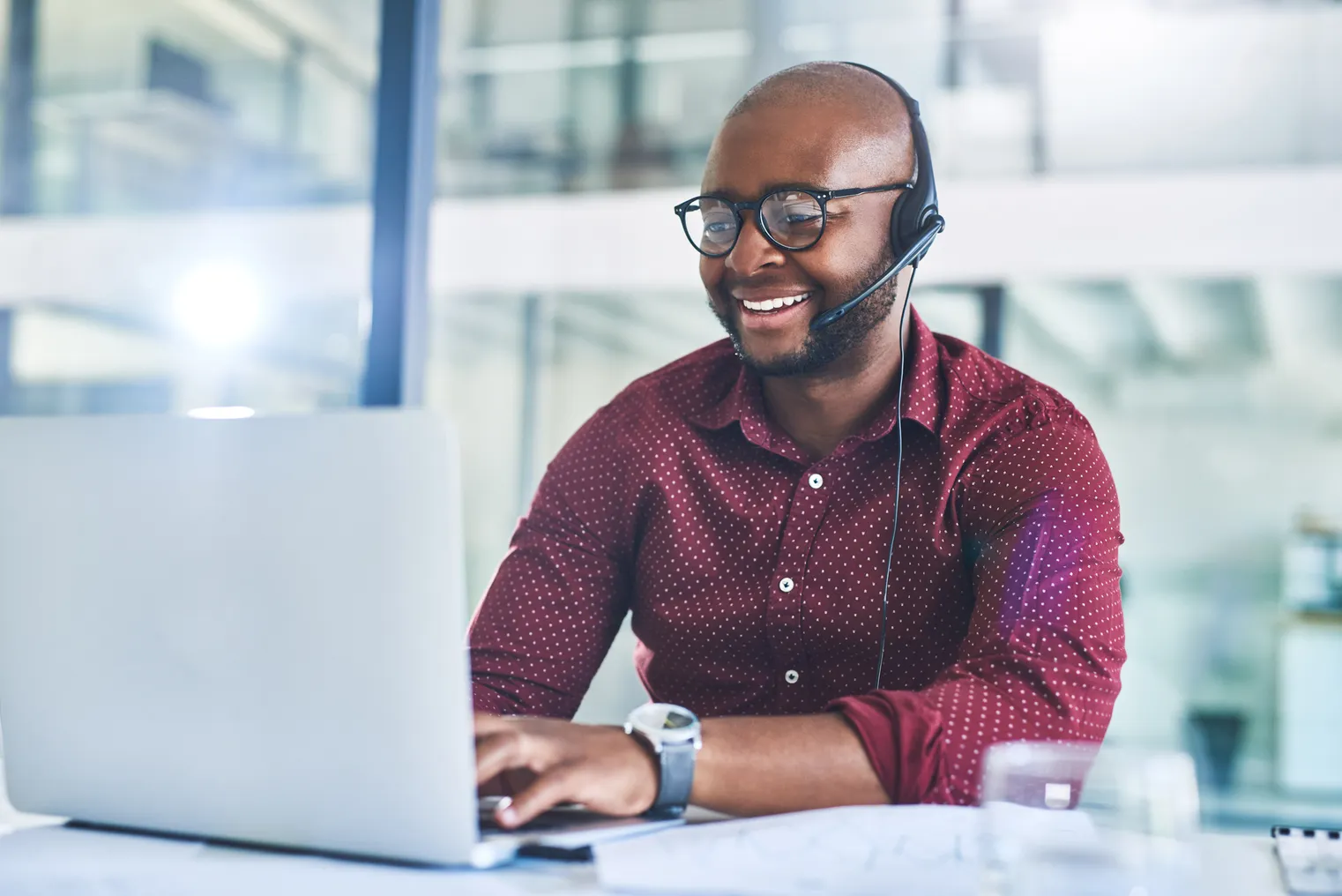 Cropped shot of a person working on a laptop with a headset