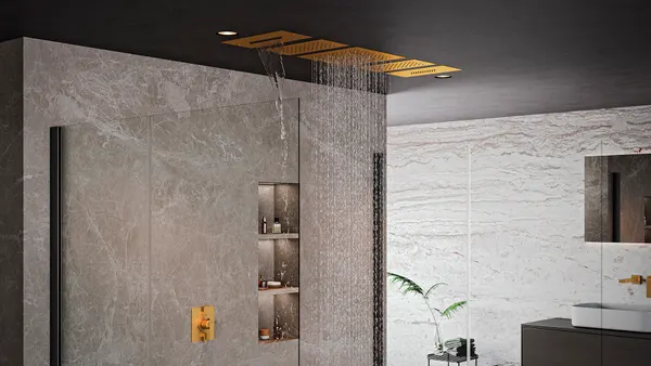 A shower with multiple golden recessed showerheads.