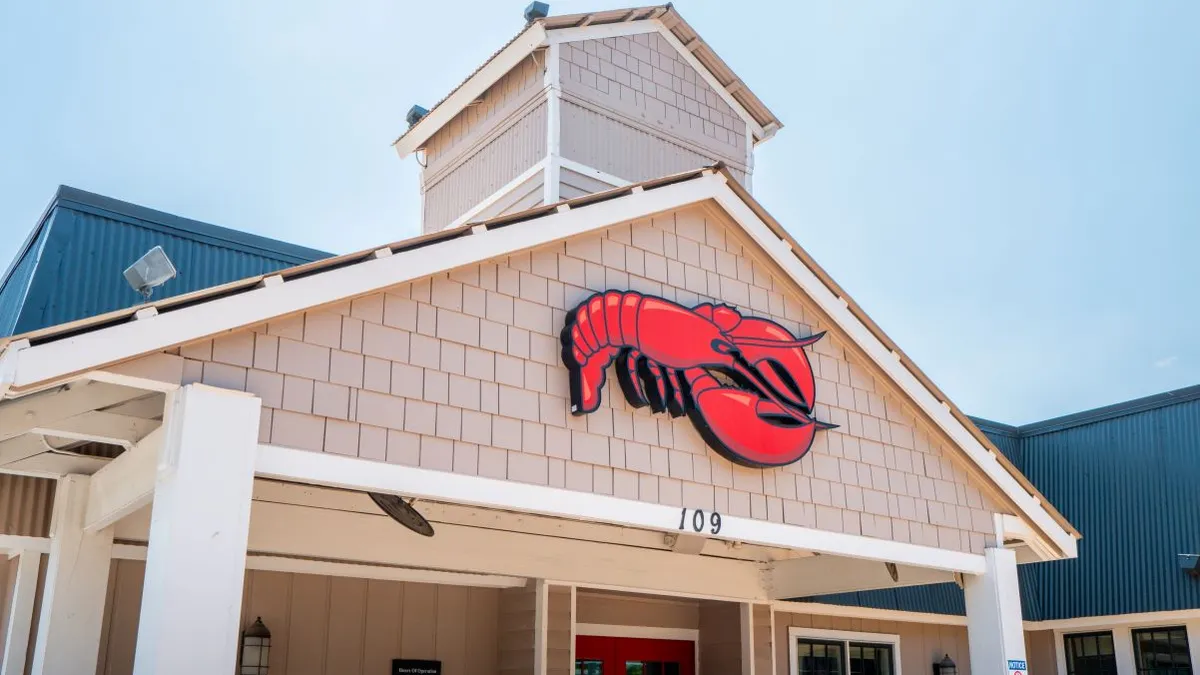 A white building with shinges and a logo of a red lobster