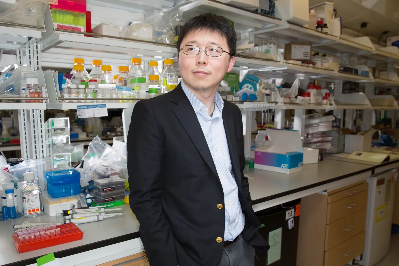 A person poses for a portrait in front a science lab.