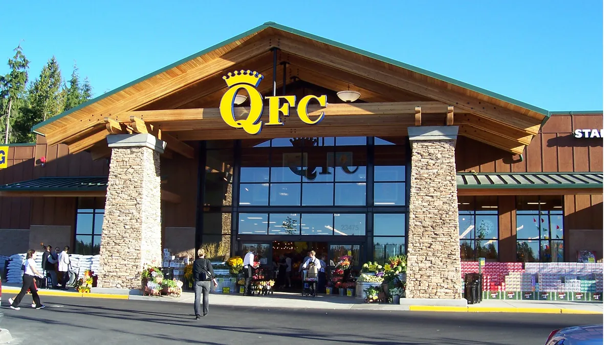 Exterior of a supermarket with a yellow "QFC" sign in front of a blue sky