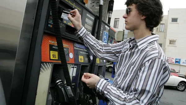 Person placing credit card into machine at gas pump.