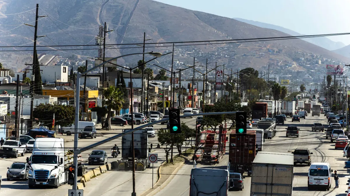 Several trucks, cars and pedestrians seen across a USA to Mexico checkpoint.