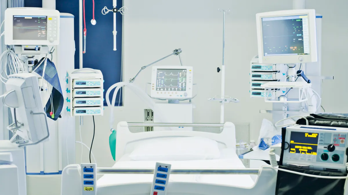 An embpty bed is surrounded by monitors and hospital equipment.