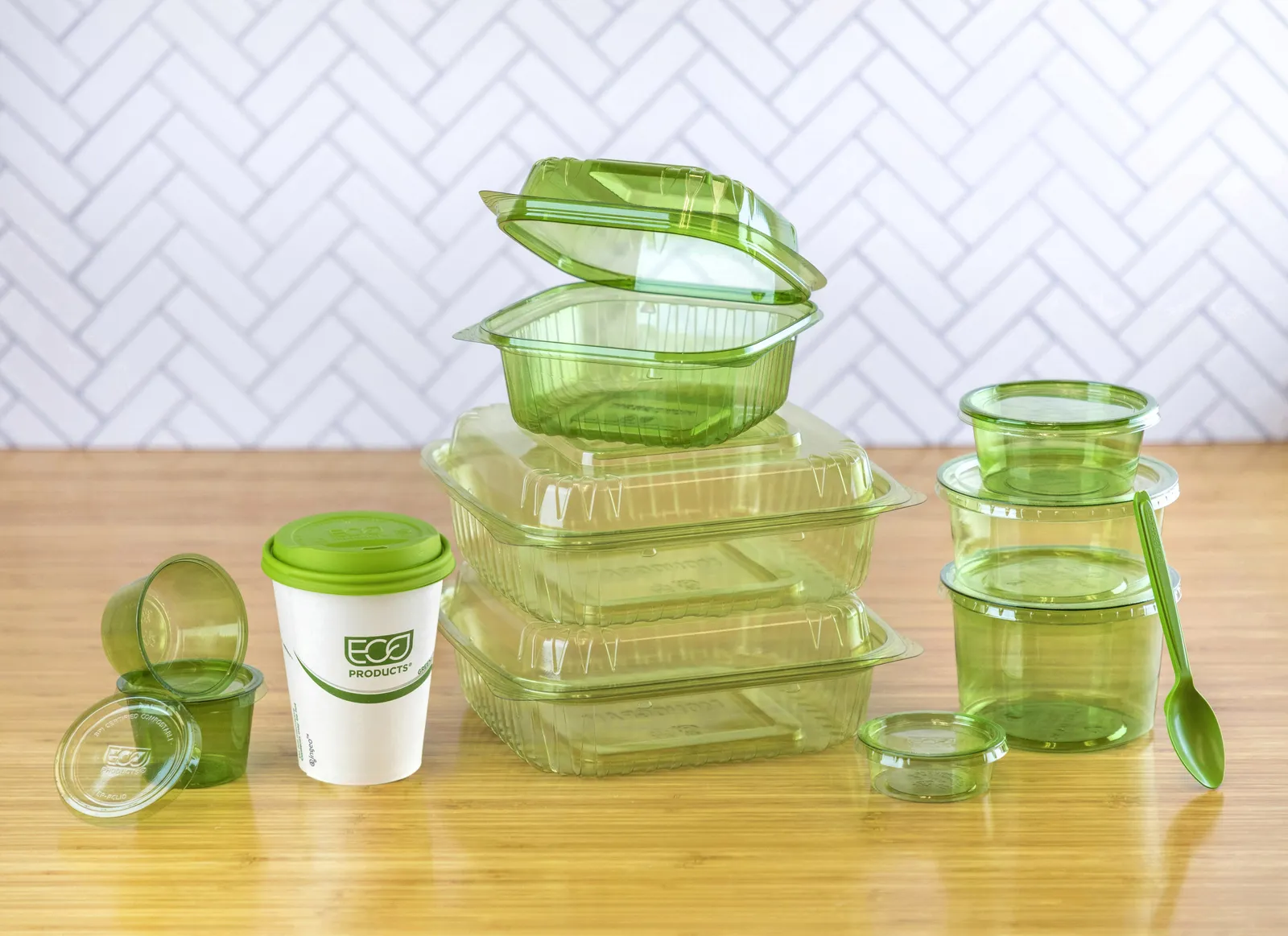 A variety of green-colored, translucent food service items including containers, cups and cutlery.