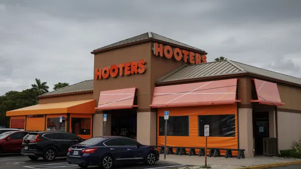 A photogrpah of a beige building with an orange sign that says Hooters.