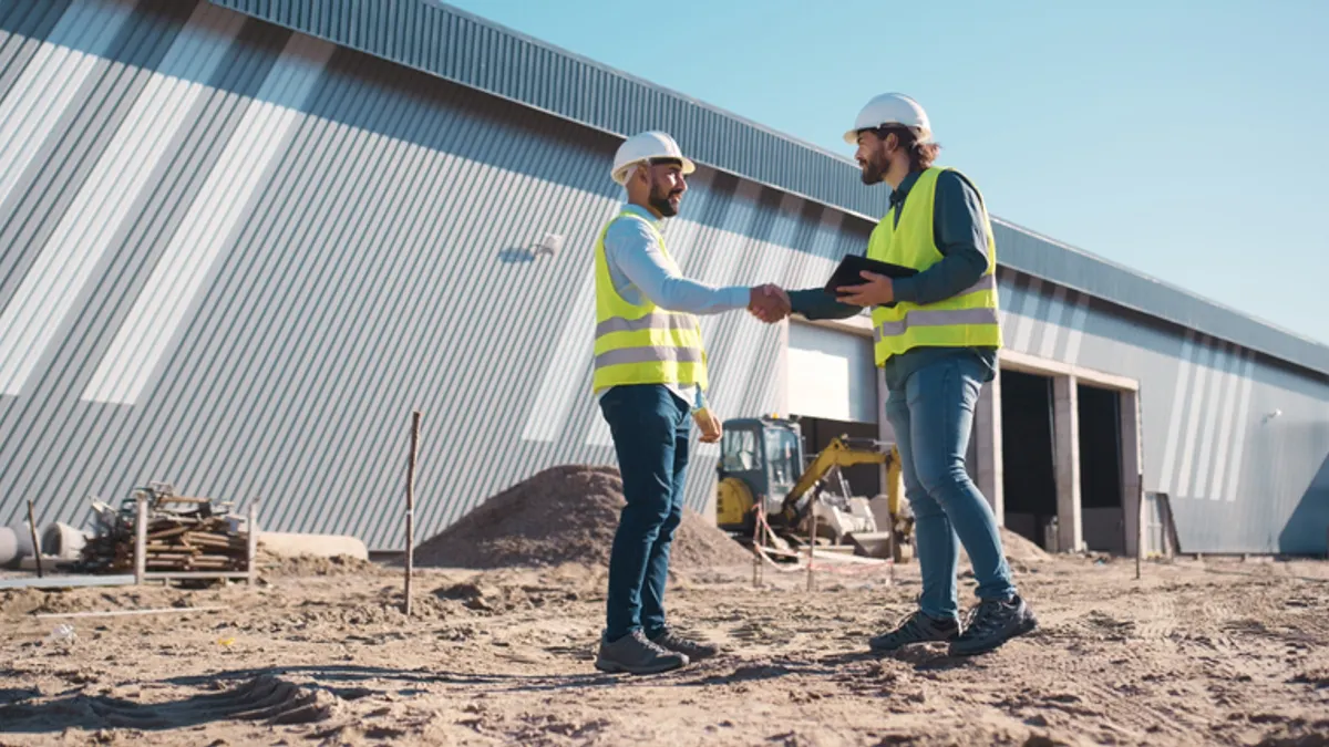 Two construction workers shake hand on a jobsite.
