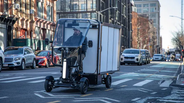 Man seated in a four-wheel cargo van in the bike lane of a New York City street.