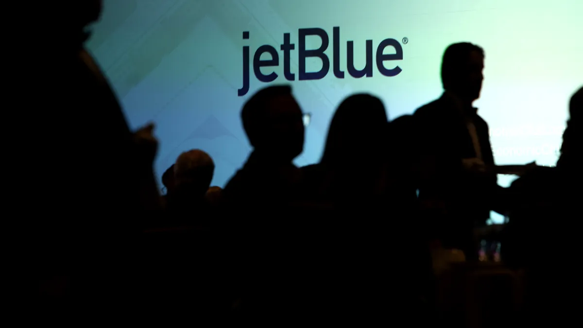 People mingle in front of a JetBlue logo.