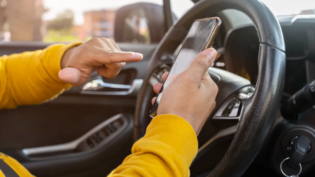 Male hand holding smartphone to use GPS navigation of travel destination and swipe to read data on navigator.