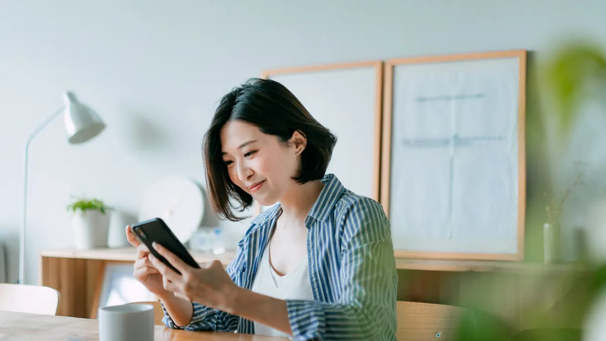 Person managing financial bill payment with smartphone and credit card in the living room at home.
