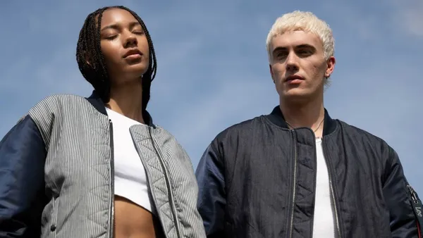 Two models stand outside together wearing jackets from the Alpha Industries and Lee Jeans collab.