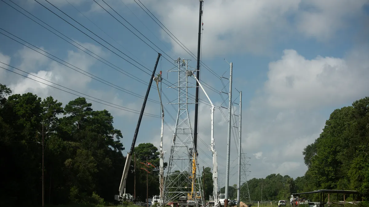 An electric utility power line crew works to upgrade a transmission line tower.