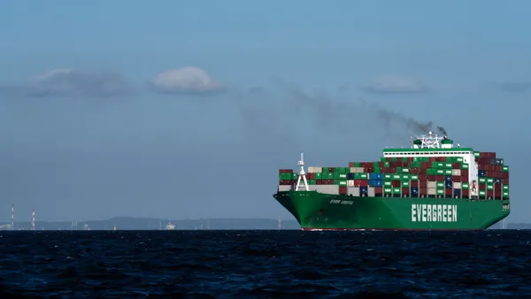 A container ship with the word "Evergreen" written on the side sails through water.