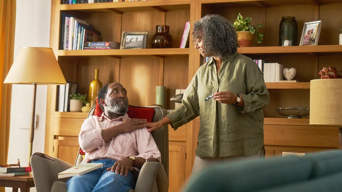 A person seated in an armchair looks up at another in this still image taken from a video commercial.