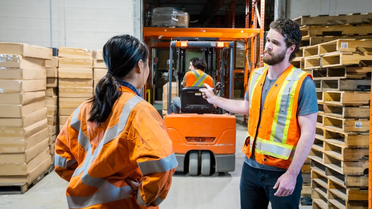 A manager discusses an issue about a forklift driver with his female colleague.