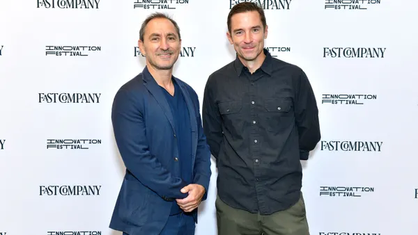 Ad executive David Droga, wearing a blue suit, stands next to Jeff Beer at a Fast Company event
