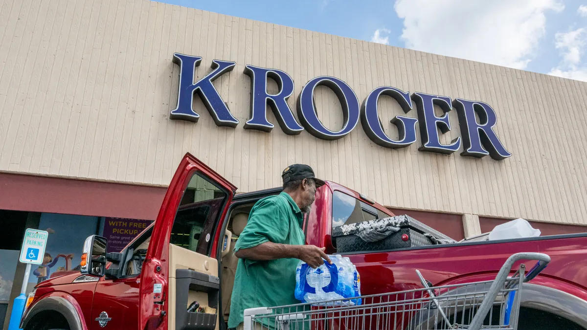 A man loads his truck in front of a Kroger store