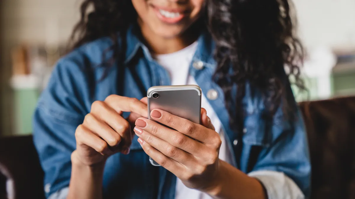 Cropped shot of a young woman using smart phone at home.