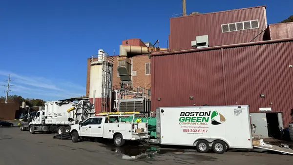A white truck with a Boston Green trailer pulled up in front of a facility
