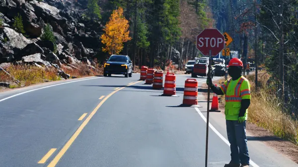 A construction worker holds a stop sign in a road work zone.