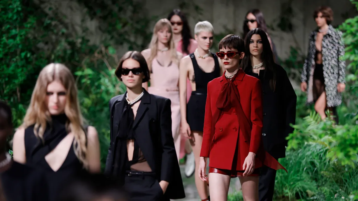 Models in colorful clothes walk en masse during a fashion show.