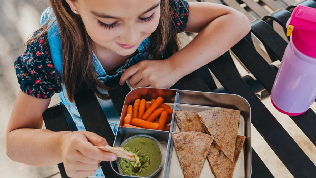 Young girl looking down at her healthy lunch on a food tray