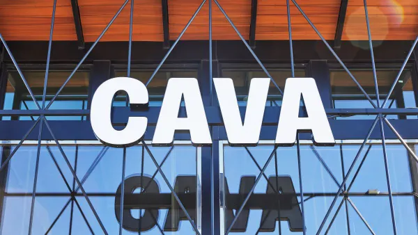 A white sign that says Cava in front of a glassed facade building.