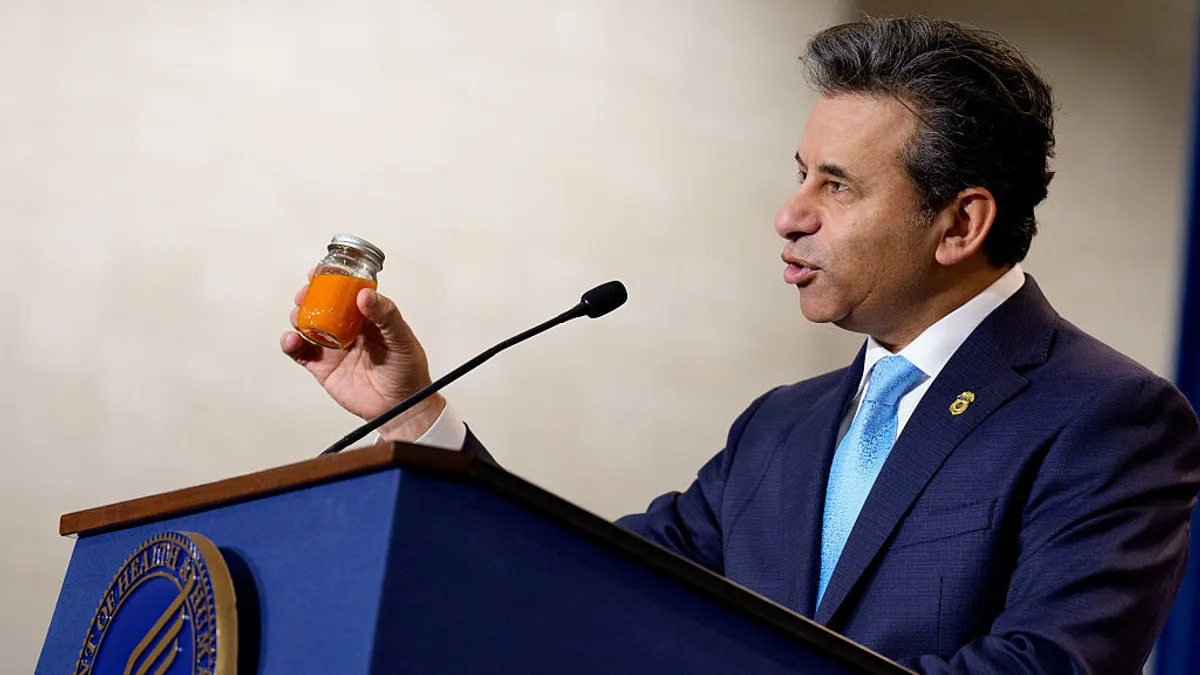 Food and Drug Administration Commissioner Marty Makary holds up a bottle of carrot juice