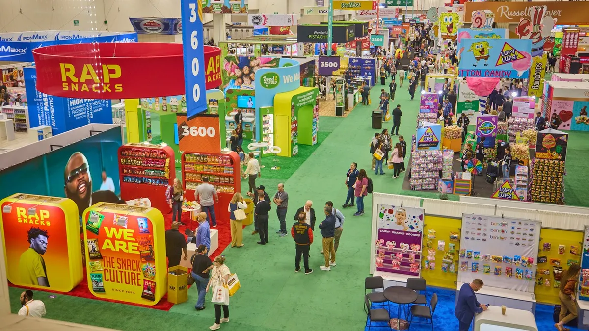 Aerial view of a convention center hall with multiple booths and patrons.