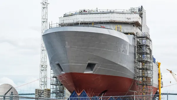 A ship that's nearly completed construction during the day.