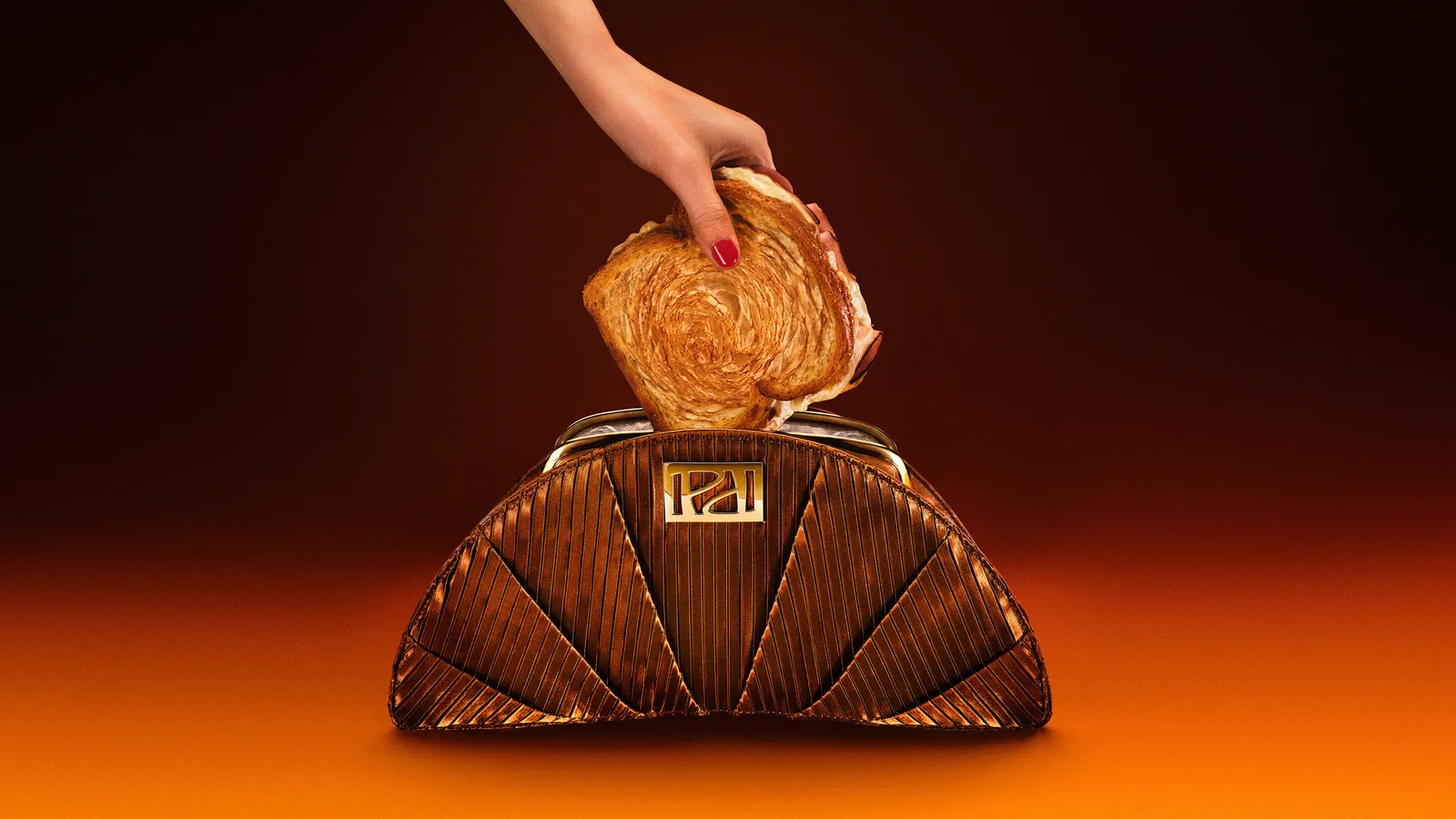 A brown croissant-looking clutch, with a person putting a sandiwch into it.