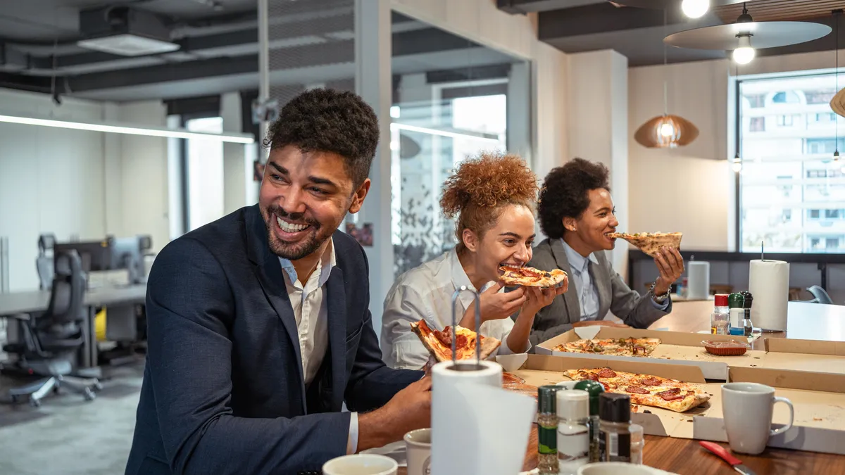 Coworkers eating a pizza and enjoy every moment of it