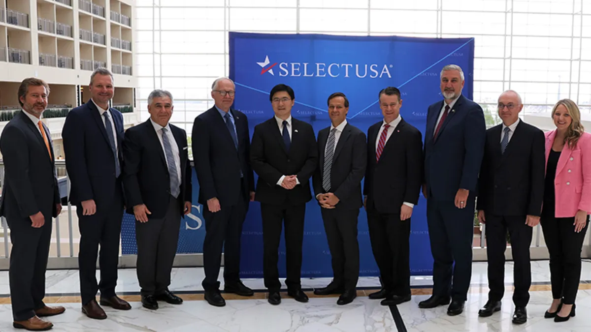 Ten people standing front of a blue drop with white capitalized serif font that says SELECT USA.