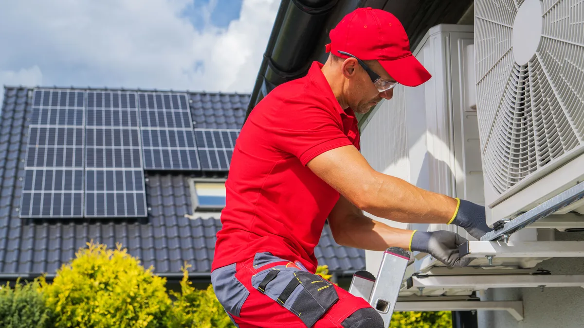 An HVAC worker is seen to perform heat pump maintenance