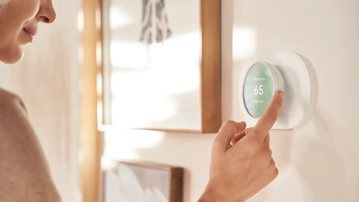 A woman adjusts a Nest thermostat.