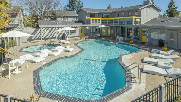 Gray apartments surrounded by pool.