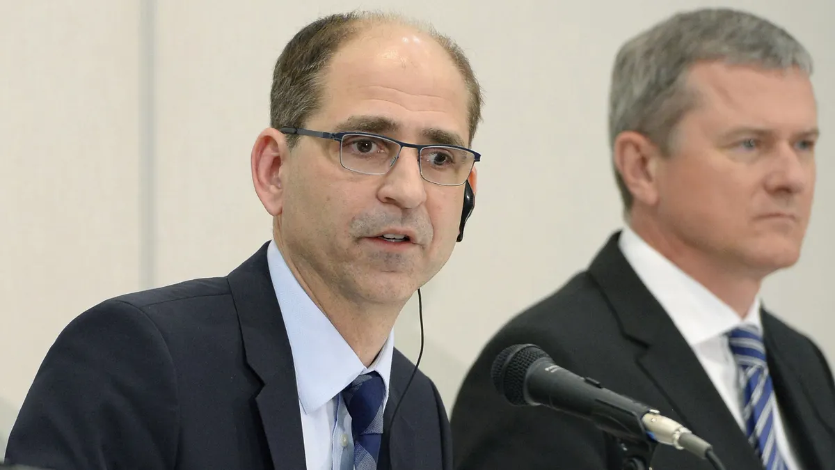 A man in a suit and tie speaks during a press conference.