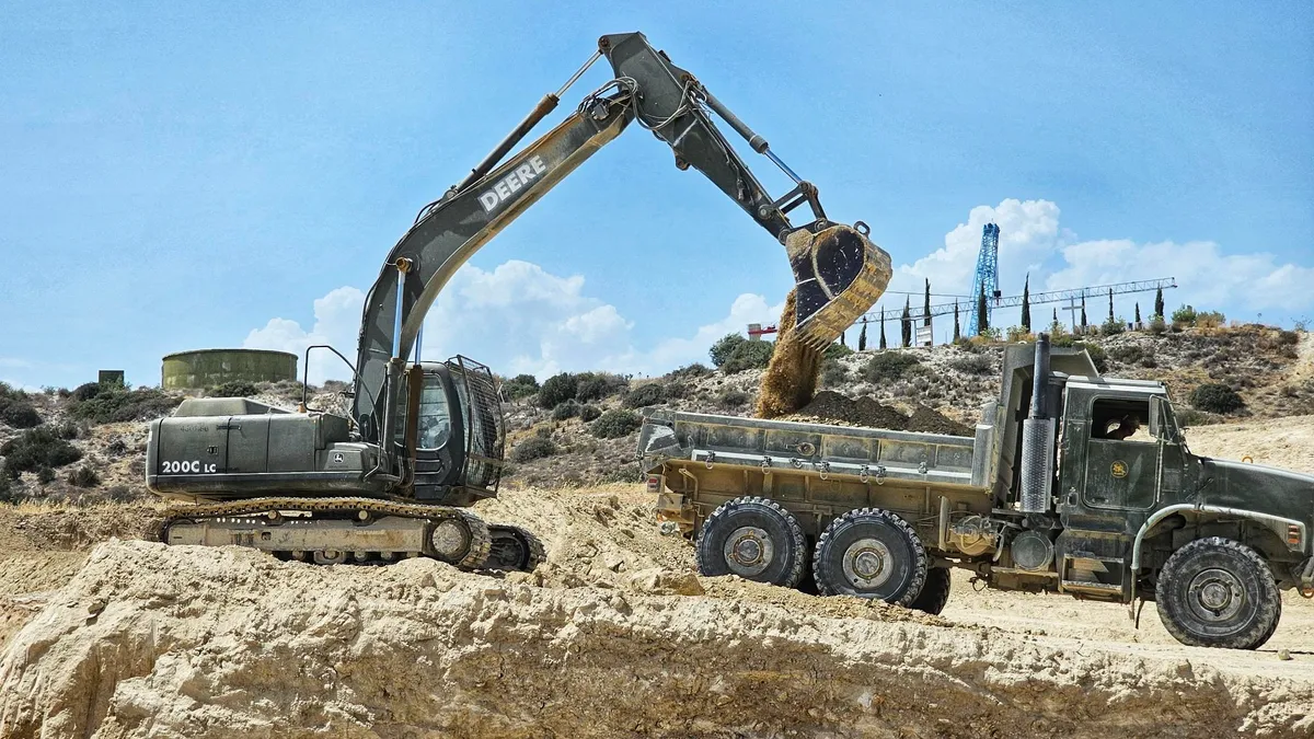 Excavator moves earth while on a helicopter landing pad site