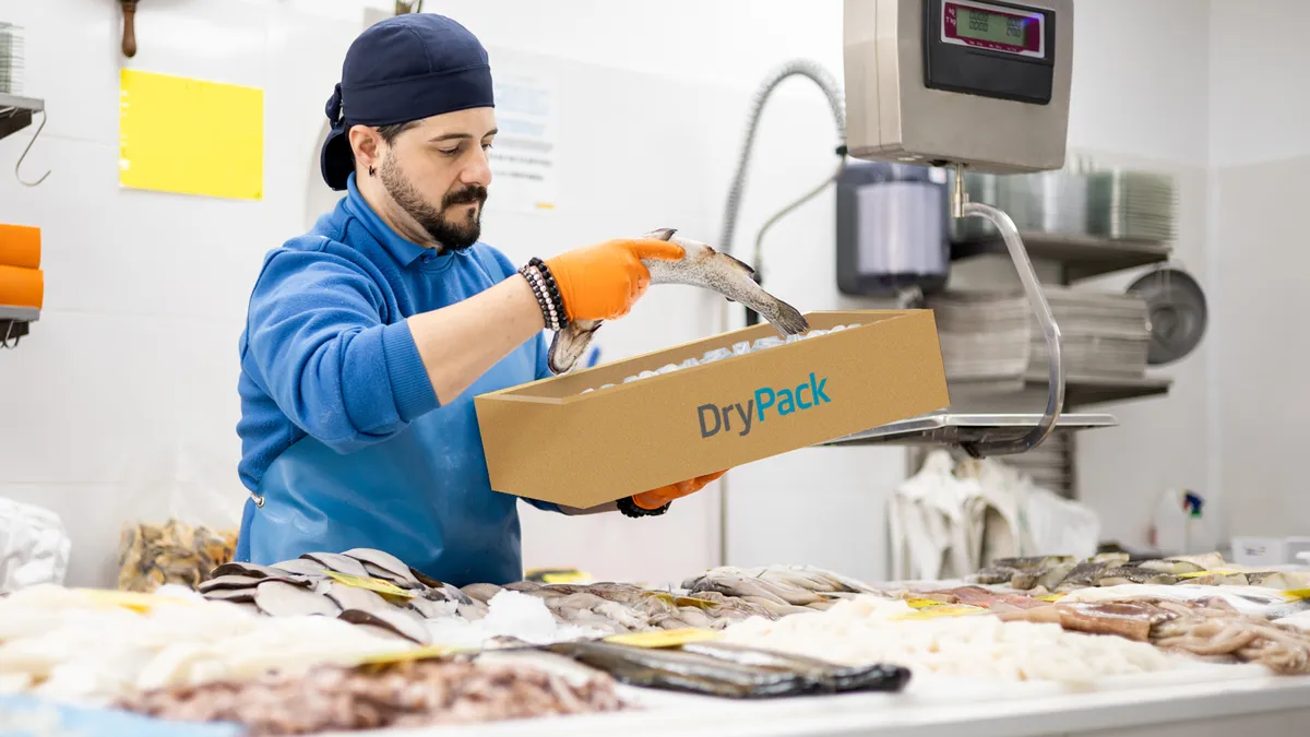 A person puts a fish in a fiber box.