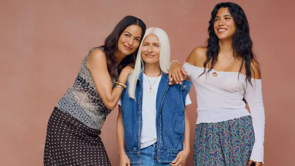 Three women pose while wearing vintage clothing.