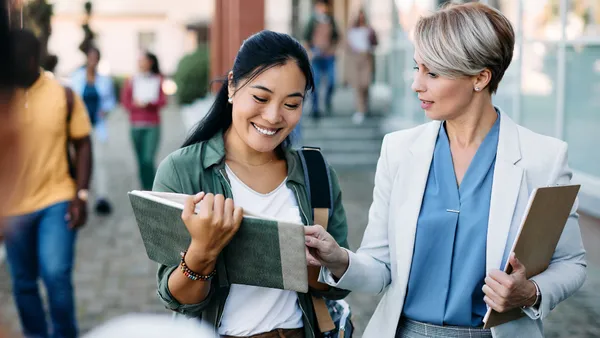 An instructor pointing in a student's book and the student smiling